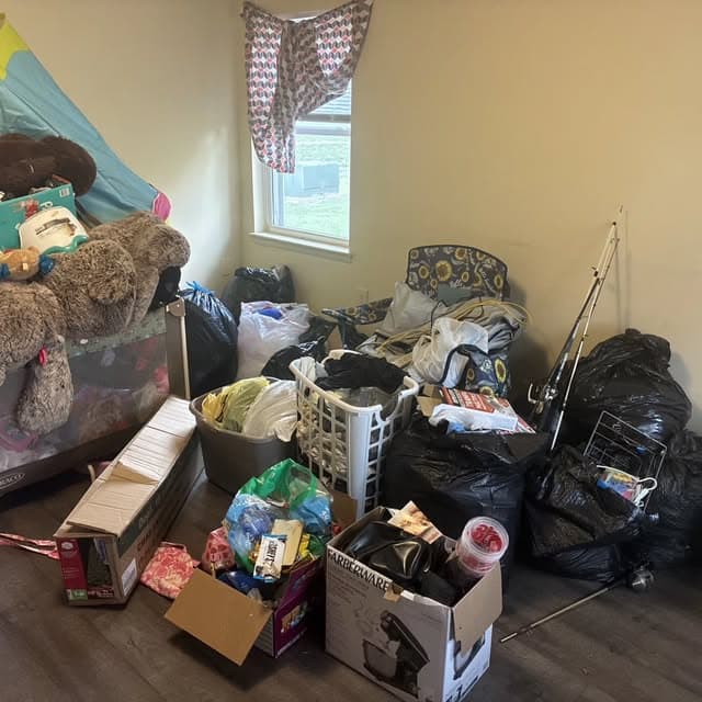 Bedroom filled with bags, boxes, and belongings before a cleanout