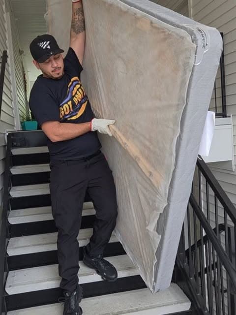 Got Junk NC crew member carrying a mattress down apartment stairs