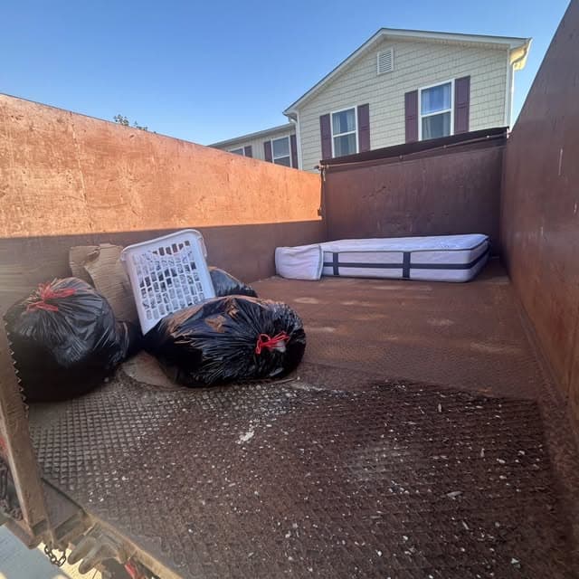 Dump body loaded with a mattress and bagged household trash