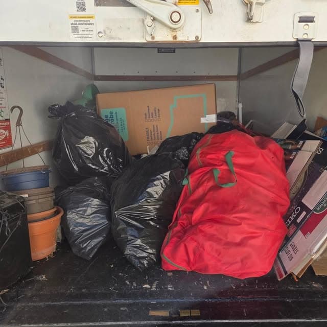 Truck loaded with bagged debris, boxes, and planters