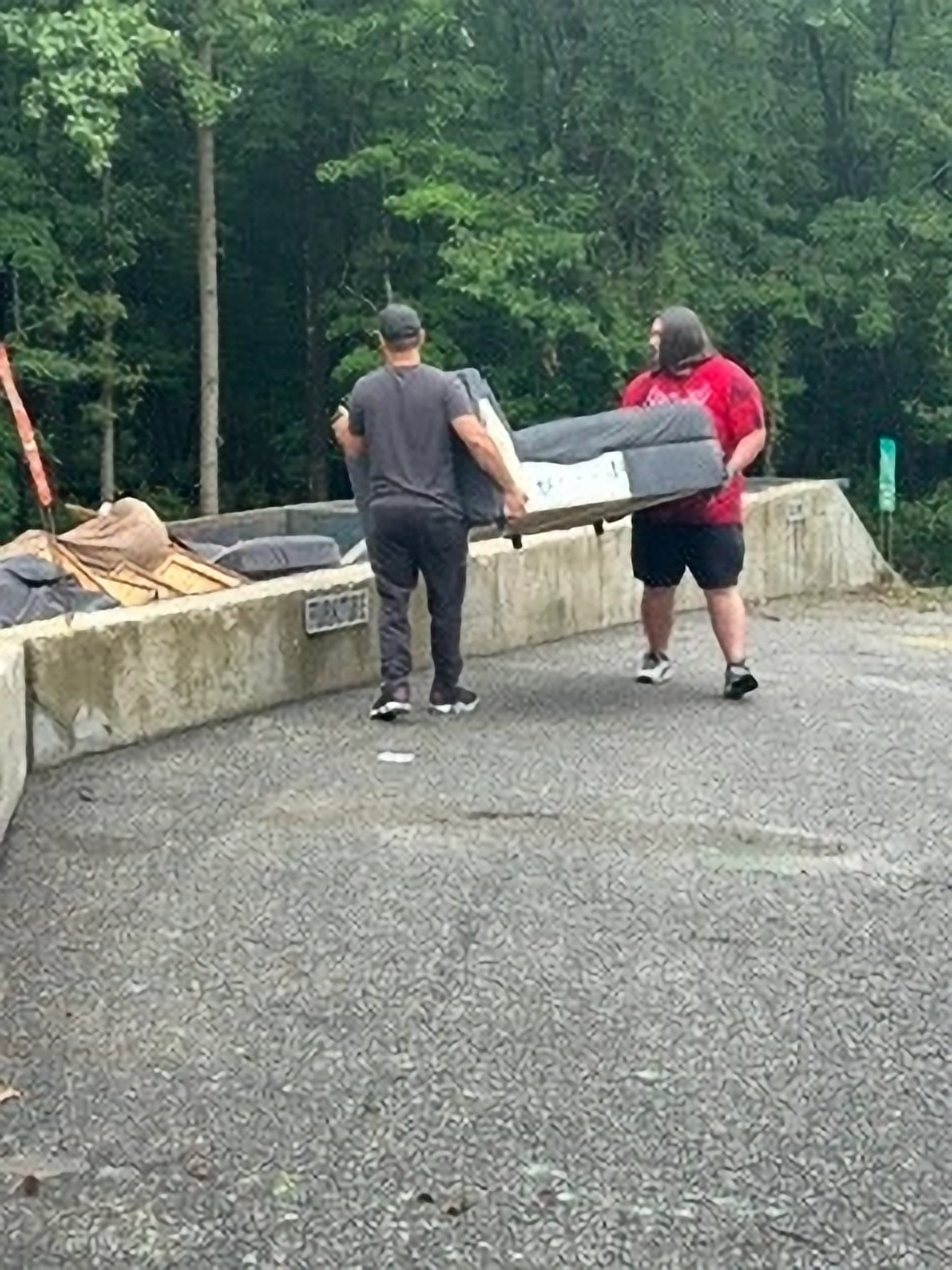 Two Got Junk NC crew members carrying a sofa out to the truck